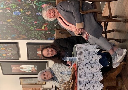 Three women sit at a table smiling