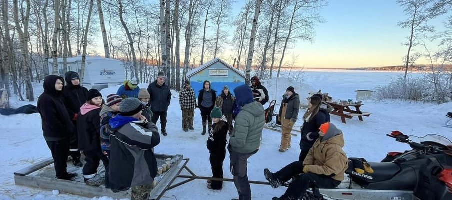 A photo of participants and facilitators in the winter camp at Kenosee Lake, smiling at the camera.