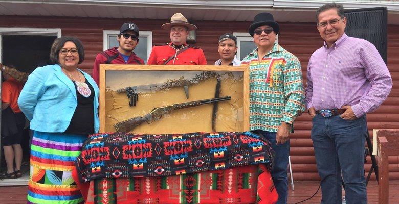 A photo of Roxanne Tootoosis, Jordan Tootoosis, Corporal Lefevbre, Lakota Tootoosis, Councilor Milton Tootoosis and Blaine Favel posing with Poundmaker’s Winchester gun and his staff, which went on display at Poundmaker Museum.