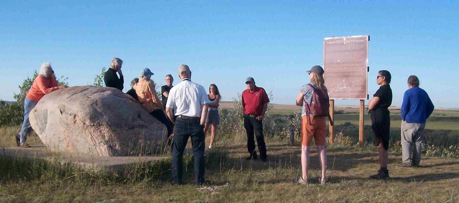 A photo of a group of people gathered in a field participating in one of the Saskatchewan History and Folklore Society-hosted walks along a historic trail.