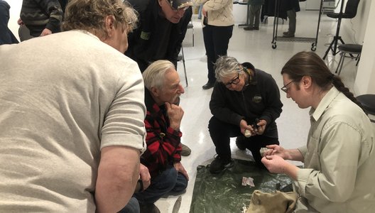 A photo of Gabriel Essaunce Lemarche, from SAS, doing a flintknapping demonstration with a small group.