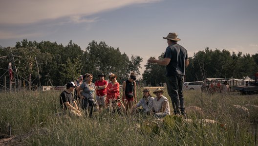 A photo of attendees of the Ness Creek Music Festival  participating in a guided forest walk, listening to someone speak.