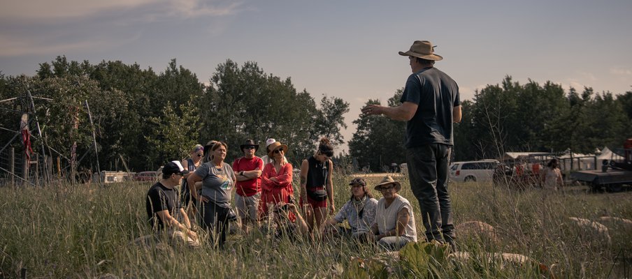 A photo of attendees of the Ness Creek Music Festival  participating in a guided forest walk, listening to someone speak.