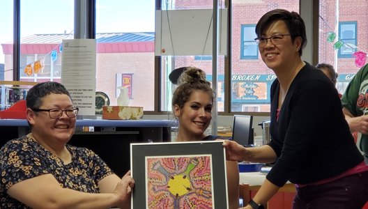 A photo of Harriet Roy (on the left), a long-time volunteer of SAS, presenting artwork.