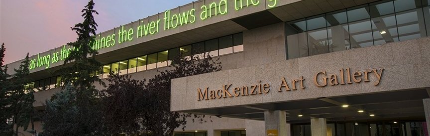 MacKenzie Art Gallery building exterior with large text installation reading "as long as the sun shines the river flows and the grass grows" on the facade.