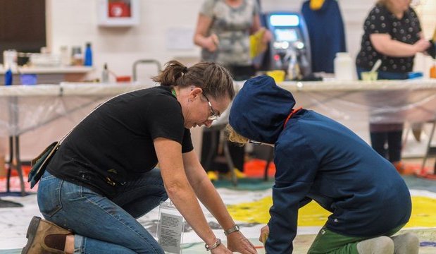 A photo of an artist and a kid working on an art piece together at a past Culture Days event.