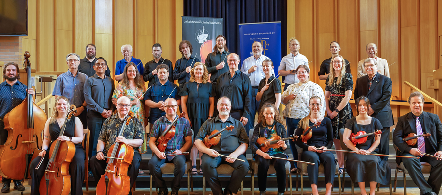 a photo of a group of orchestra members sitting and holding violins