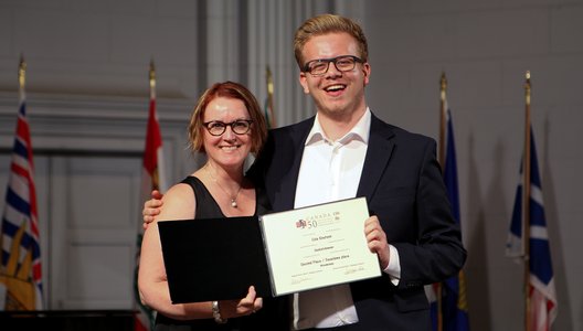 A photo of Cole Knutson hugging a person, receiving a diploma.