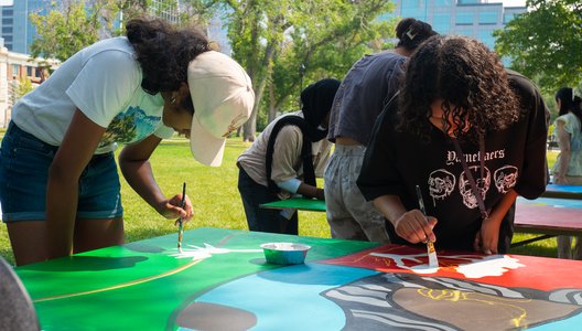 A photo of newcomer youth painting at an event by the Regina Open Door Society.