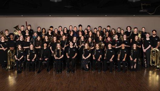 A group photo of kids in a school band, posing with their instruments.