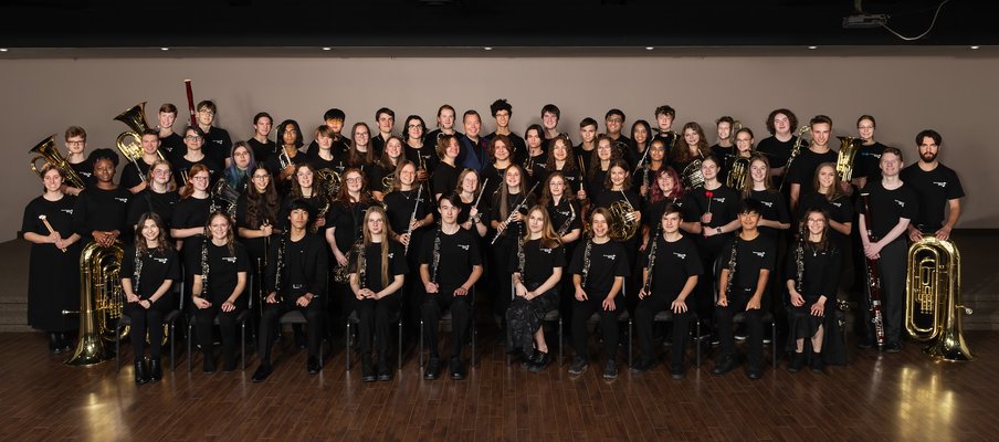 A group photo of kids in a school band, posing with their instruments.