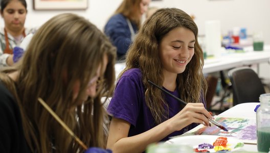 A photo of two young people painting and smiling at a Culture Days 2024 activity.