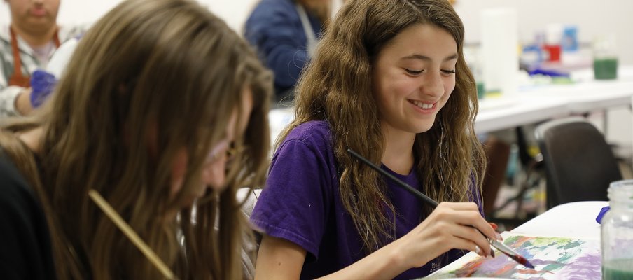 A photo of two young people painting and smiling at a Culture Days 2024 activity.