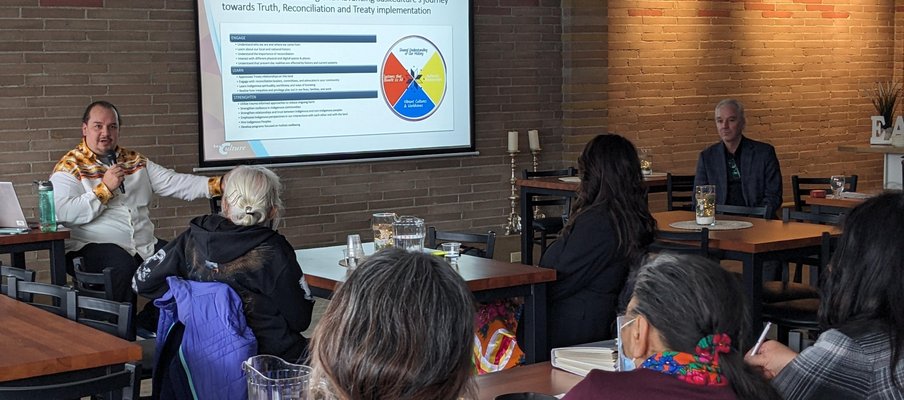 A photo of Damon Badger Heit, SaskCulture Supervisor, Partnerships and Inclusion, presenting at an event.