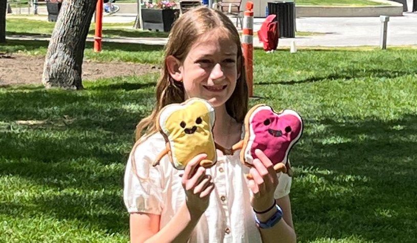 Young girl holding up the stuffed animals she created to raise money for Creative Kids