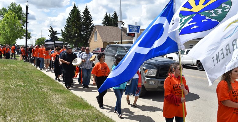 A group of community members in orange shirts walking together at a Reconciliation event.