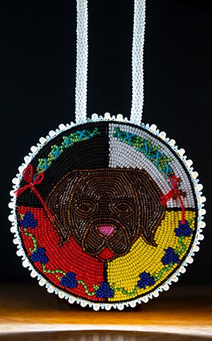 a colourful beaded medallion with a dogs face on it